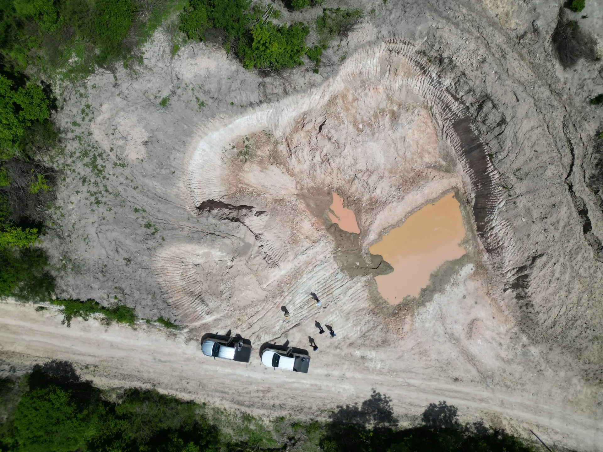 Top-down drone view of the Arapaima excavation, two muddy pools, access road and vehicles